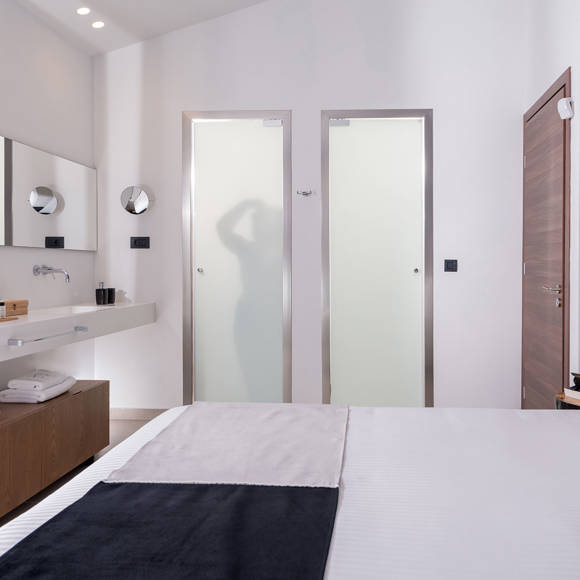 Grand villa master bedroom with modern ensuite bathroom featuring double mirrors and frosted glass doors 