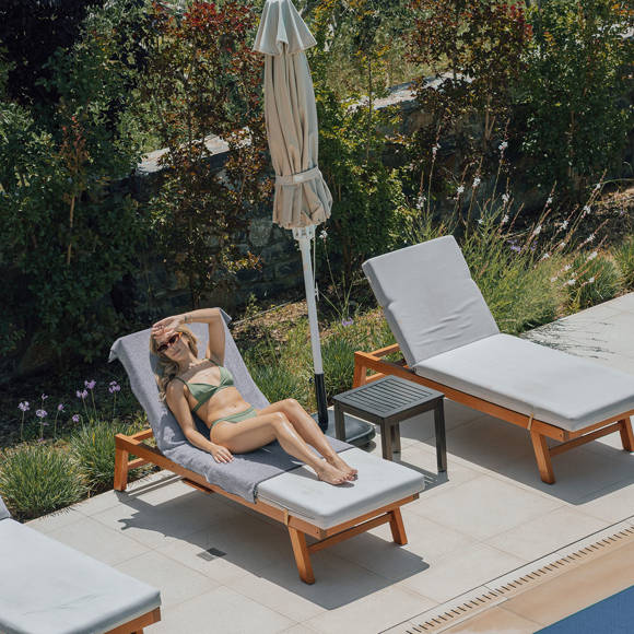 Guest enjoying the sun on a poolside lounger surrounded by greenery at Avdou Collection Crete