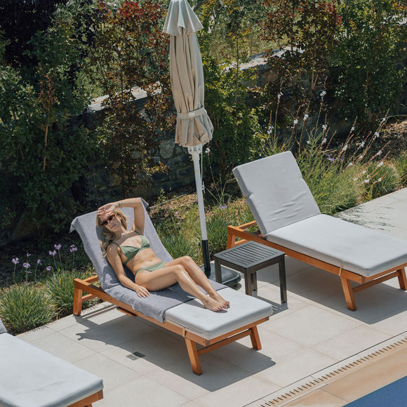 Guest enjoying the sun on a poolside lounger surrounded by greenery at Avdou Collection Crete