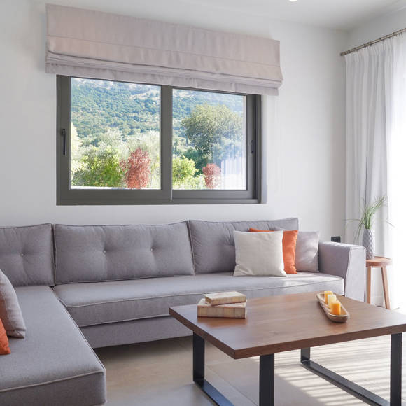 Grand villa living area with corner sofa, colorful cushions, coffee table and large window at Avdou Collection Crete