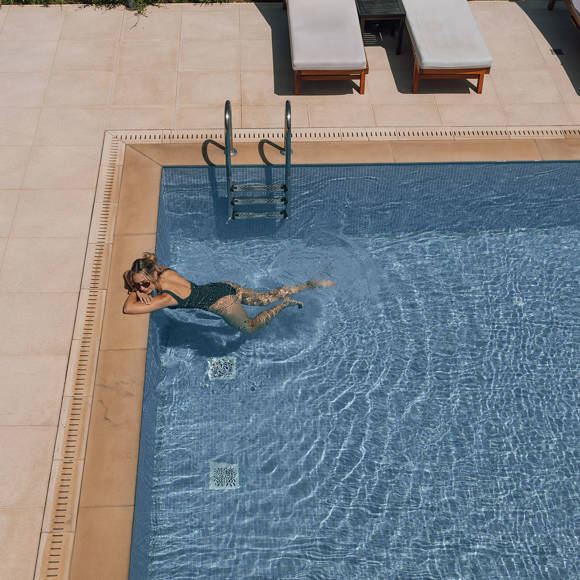 Guest relaxing in the clear blue swimming pool under the sun in Avdou Collection Crete