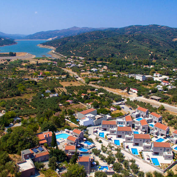 Aerial view of Avdou Collection surrounded by olive groves and mountains near the scenic lake in Crete