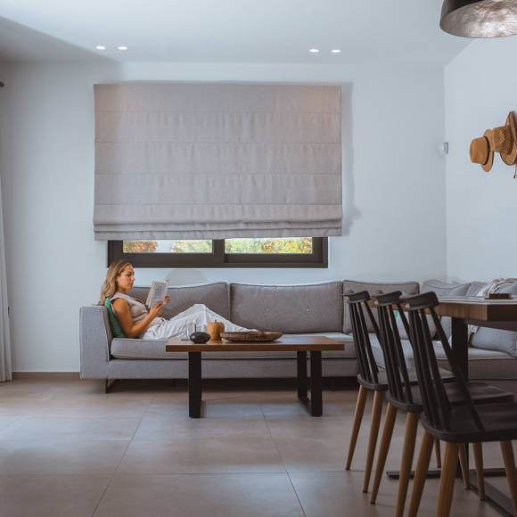 Guest relaxing with a book in the bright living room of a modern villa at Avdou Collection Crete