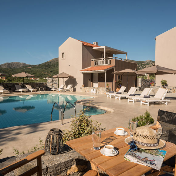 Relaxing poolside setting with sun loungers, umbrellas and mountain views at Avdou Collection Crete