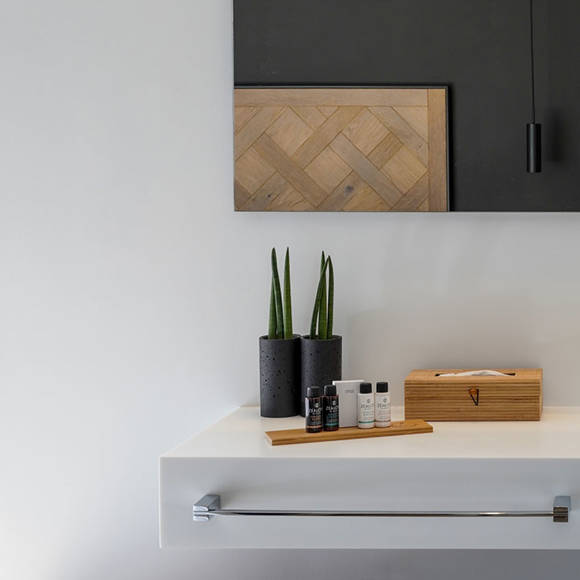 Grand villa bathroom detail with fresh towels, toiletries, wooden tissue bod and modern decor at Avdou Collection