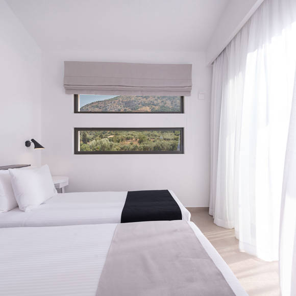 Three bedroom grand villa with twin beds placed by large windows with views of the Cretan hills and soft light