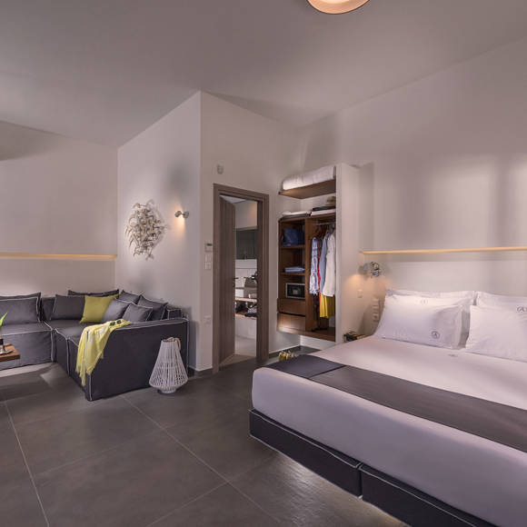 Open plan suite with double bed, sofa open wardrobe and minimalist decor at Avdou Collection Crete