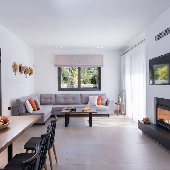 Grand villa living room with corner sofa, fireplace, wall mounted TV and dining table at Avdou Collection Crete