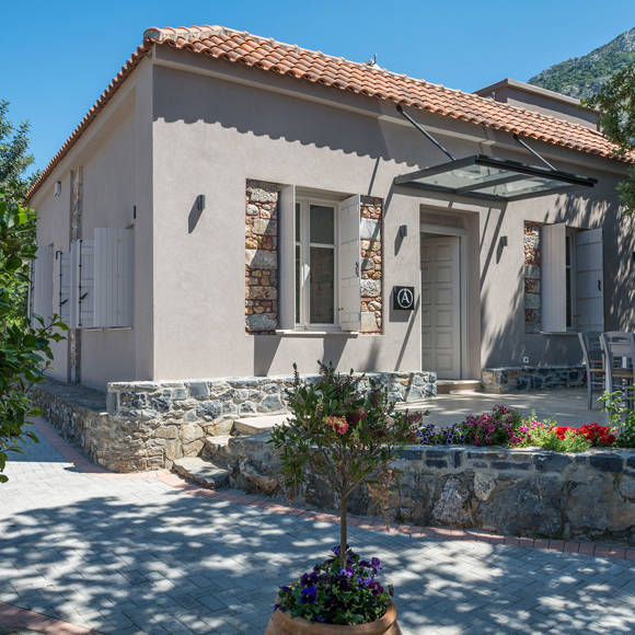 Charming cafe restaurant with stone details, outdoor seating and colorful flowers at Avdou Collection Crete